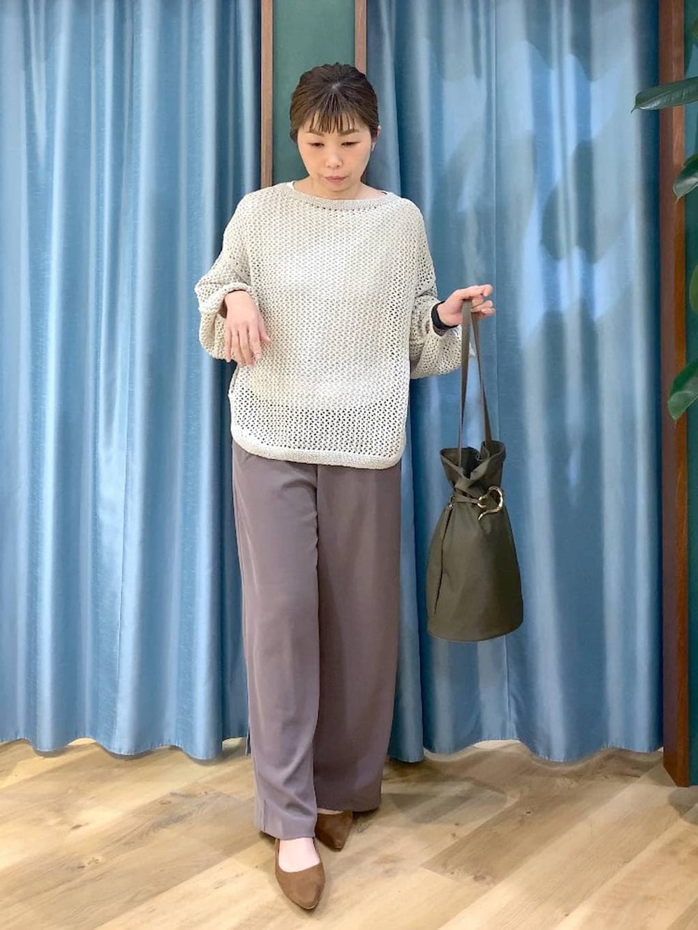 グリーン系のスラックス、ベージュ系のニット/セーター、ホワイト系のTシャツ/カットソーを着用したレディースの冬コーディネートの4枚目の写真