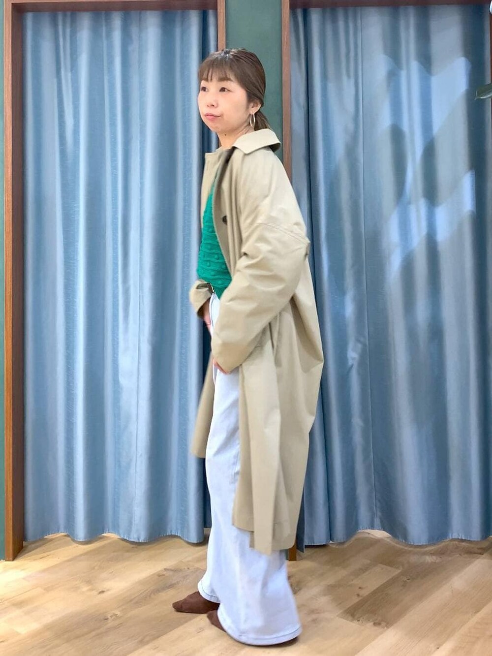 ブラウン系のパンプス、ブルー系のデニムパンツ、グリーン系のニット/セーターを着用したレディースの冬コーディネートの3枚目の写真