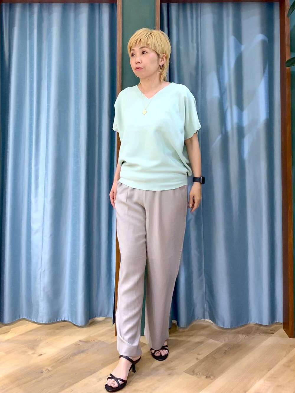 グリーン系のニット/セーター、ベージュ系のその他パンツ、ブラック系のサンダルを着用したレディースの春コーディネートの2枚目の写真