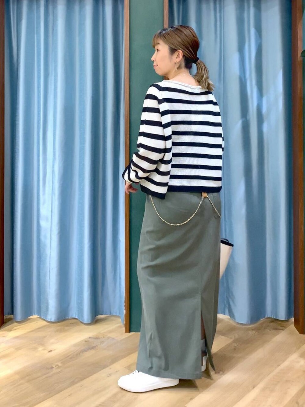 ベージュ系のニット/セーター、グリーン系のスカート、ホワイト系のトートバッグを着用したレディースの春コーディネートの7枚目の写真