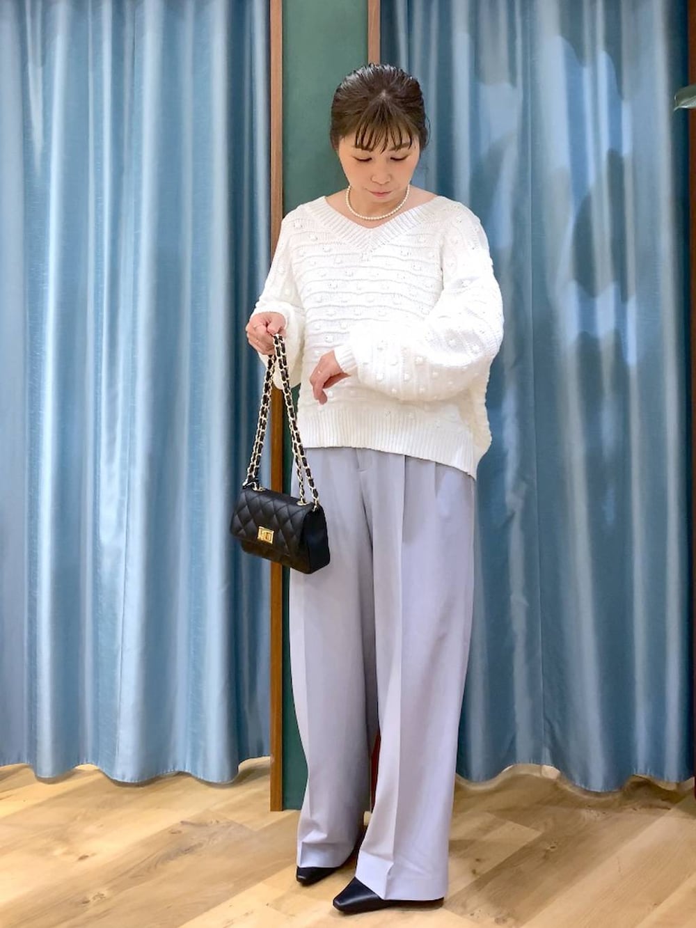 ホワイト系のニット/セーター、グレー系のその他パンツ、ブラック系のショルダーバッグを着用したレディースの冬コーディネートの6枚目の写真