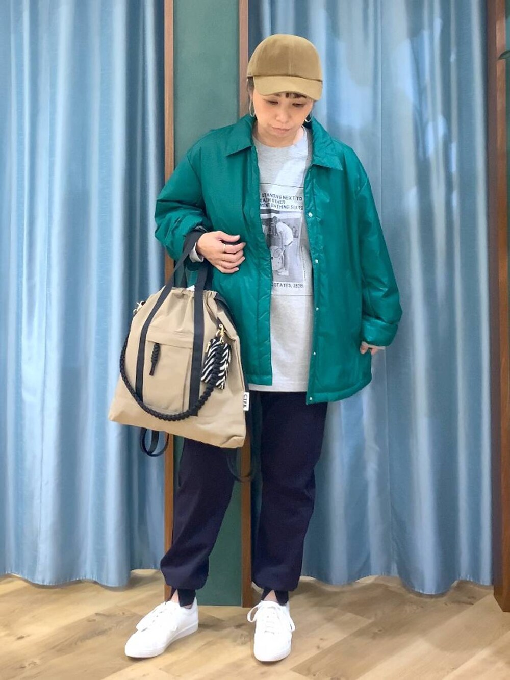 グリーン系のブルゾン、ブルー系のその他パンツ、ブラウン系のバックパック/リュックを着用したレディースの秋コーディネートの2枚目の写真
