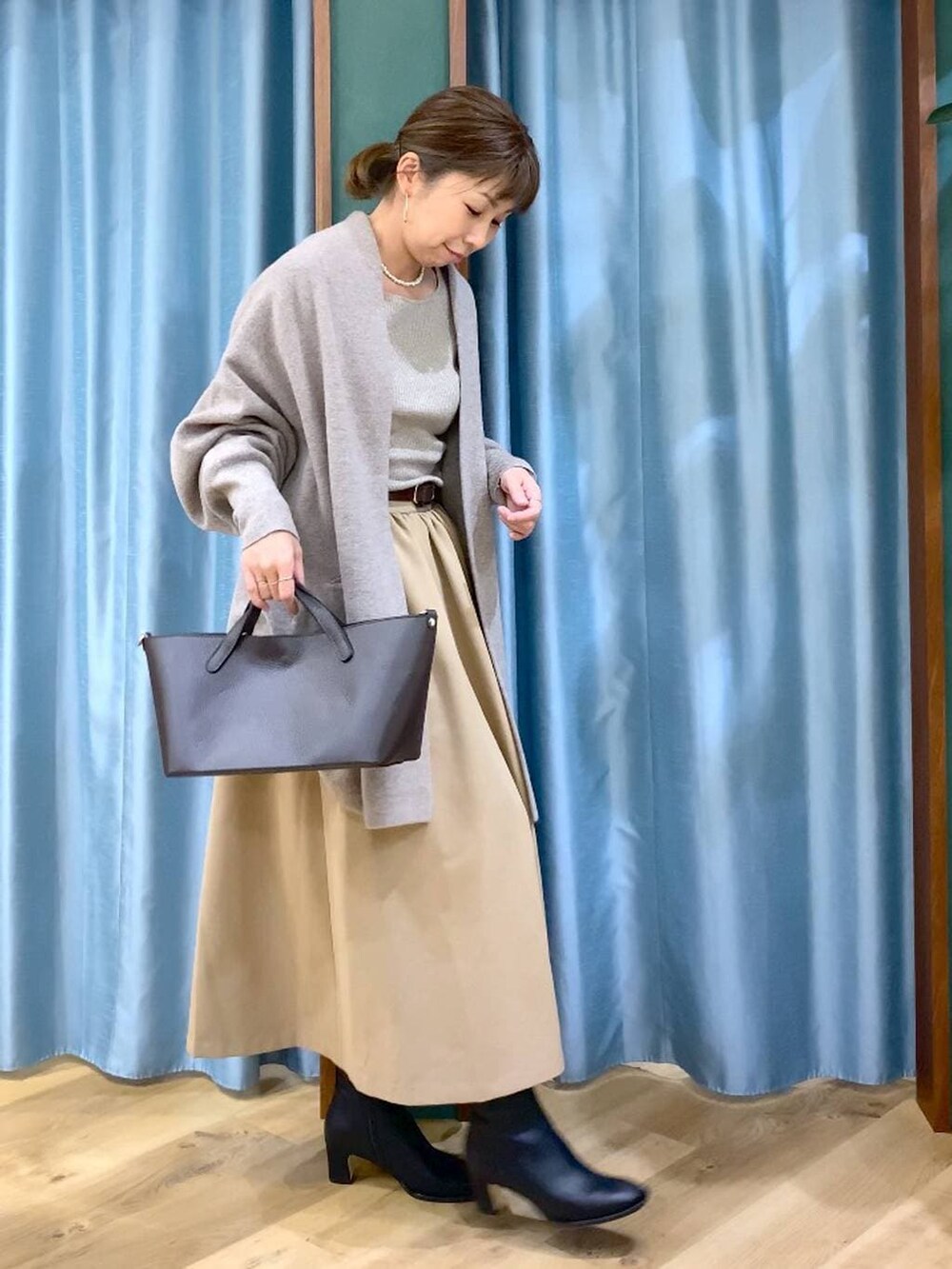 ブラック系のブーツ、ベージュ系のニット/セーター、ブラウン系のショルダーバッグを着用したレディースの秋コーディネートの2枚目の写真
