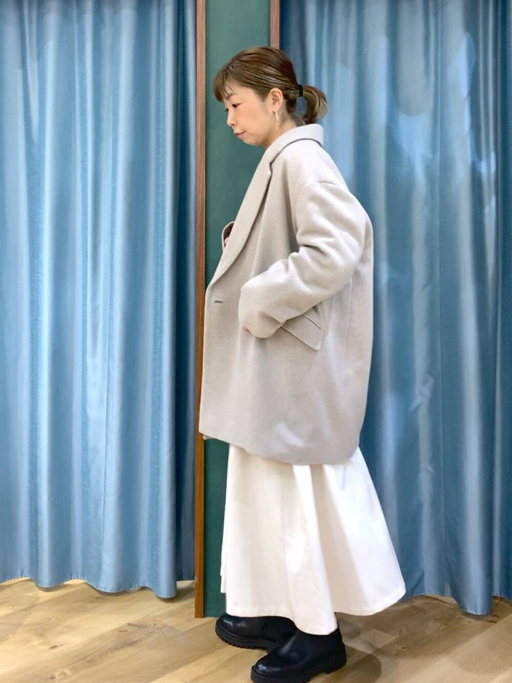 ブラック系のブーツ、ベージュ系のピーコート、ホワイト系のスカートを着用したレディースの冬コーディネートの4枚目の写真