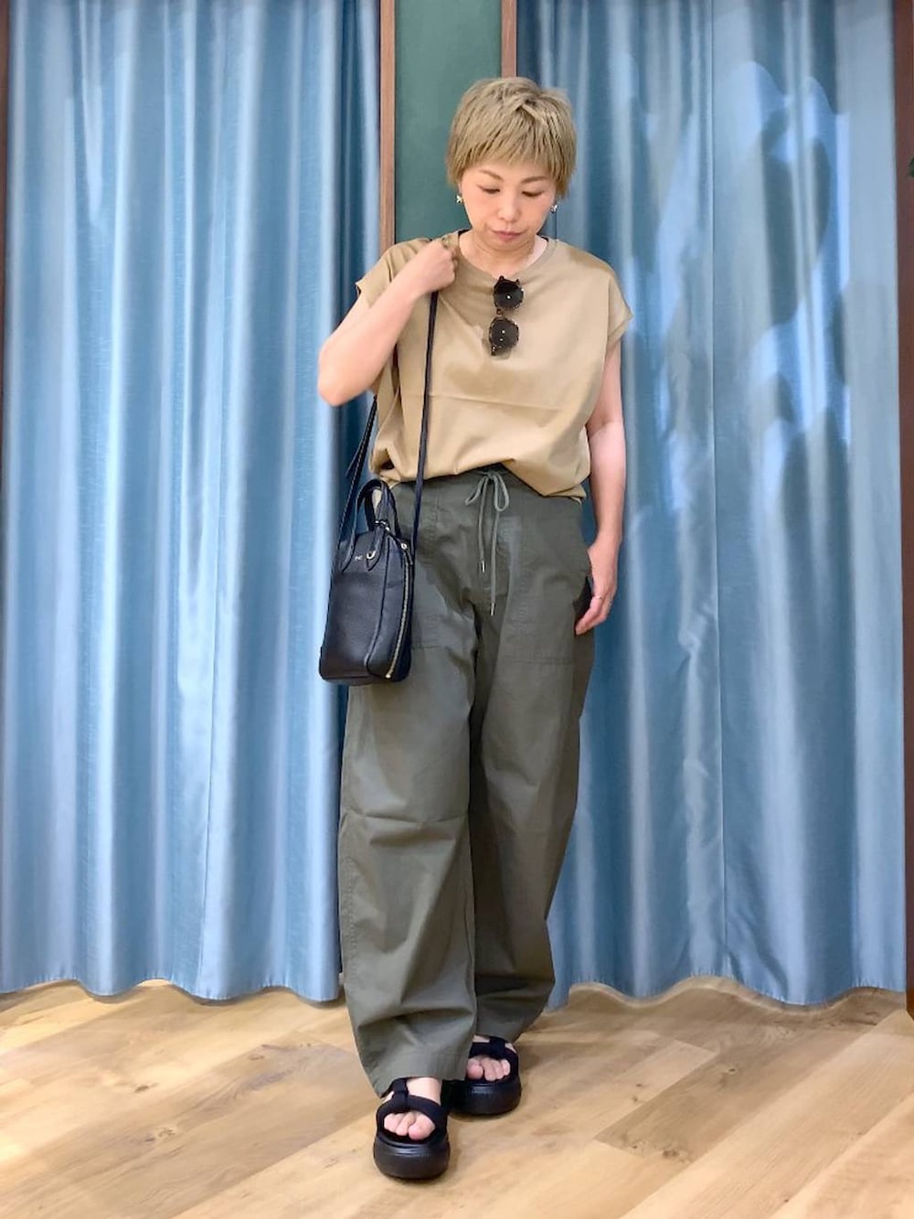 ブラック系のショルダーバッグ、グリーン系のカーゴパンツ、ブラック系のサンダルを着用したレディースの夏コーディネートの3枚目の写真