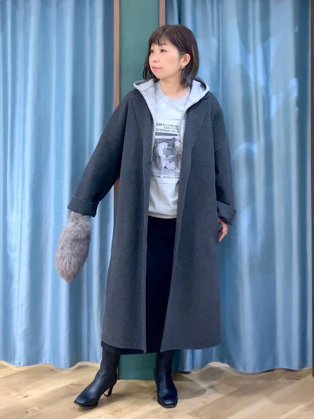 ブラウン系のトートバッグ、グレー系のチェスターコート、ブラック系のスカートを着用したレディースの秋コーディネートの2枚目の写真