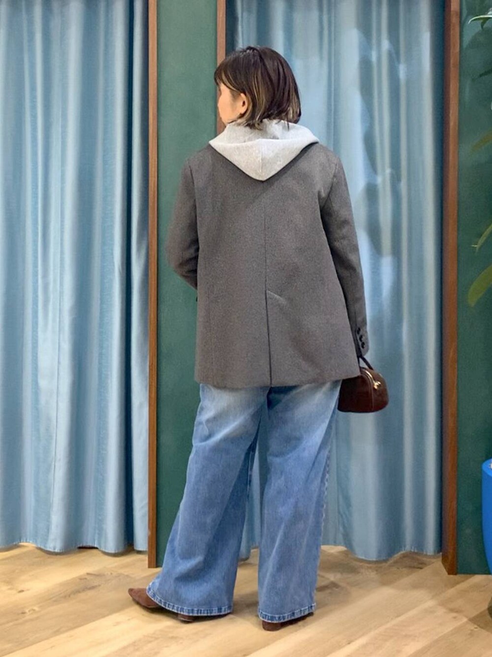 ブルー系のデニムパンツ、ブラウン系のテーラードジャケット、グレー系のパーカーを着用したレディースの秋コーディネートの3枚目の写真