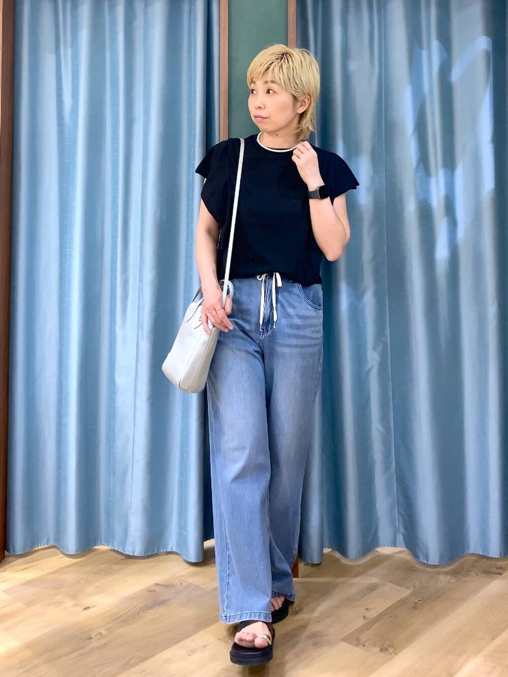 ブルー系のデニムパンツ、シルバー系のショルダーバッグ、ブラック系のニット/セーターを着用したレディースの夏コーディネートの3枚目の写真