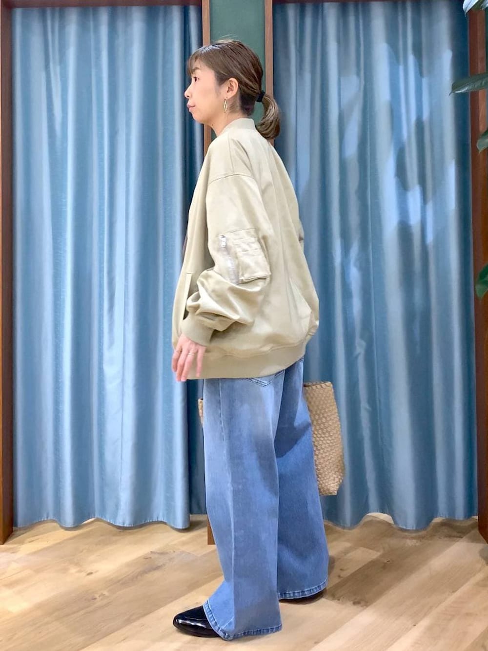 ブルー系のデニムパンツ、ベージュ系のMA-1、グリーン系のTシャツ/カットソーを着用したレディースの冬コーディネートの3枚目の写真