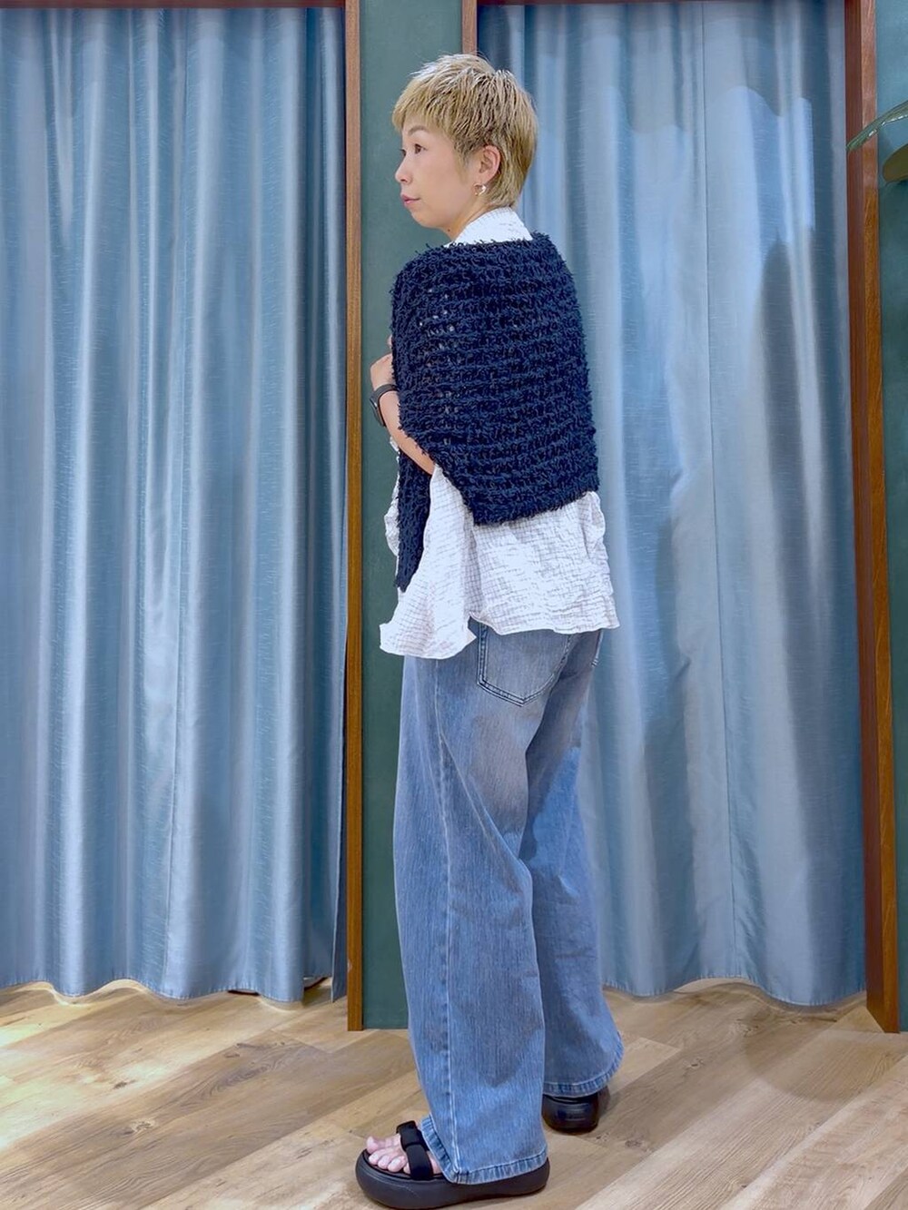 ブルー系のデニムパンツ、ブラック系のサンダル、ホワイト系のシャツ/ブラウスを着用したレディースの夏コーディネートの4枚目の写真