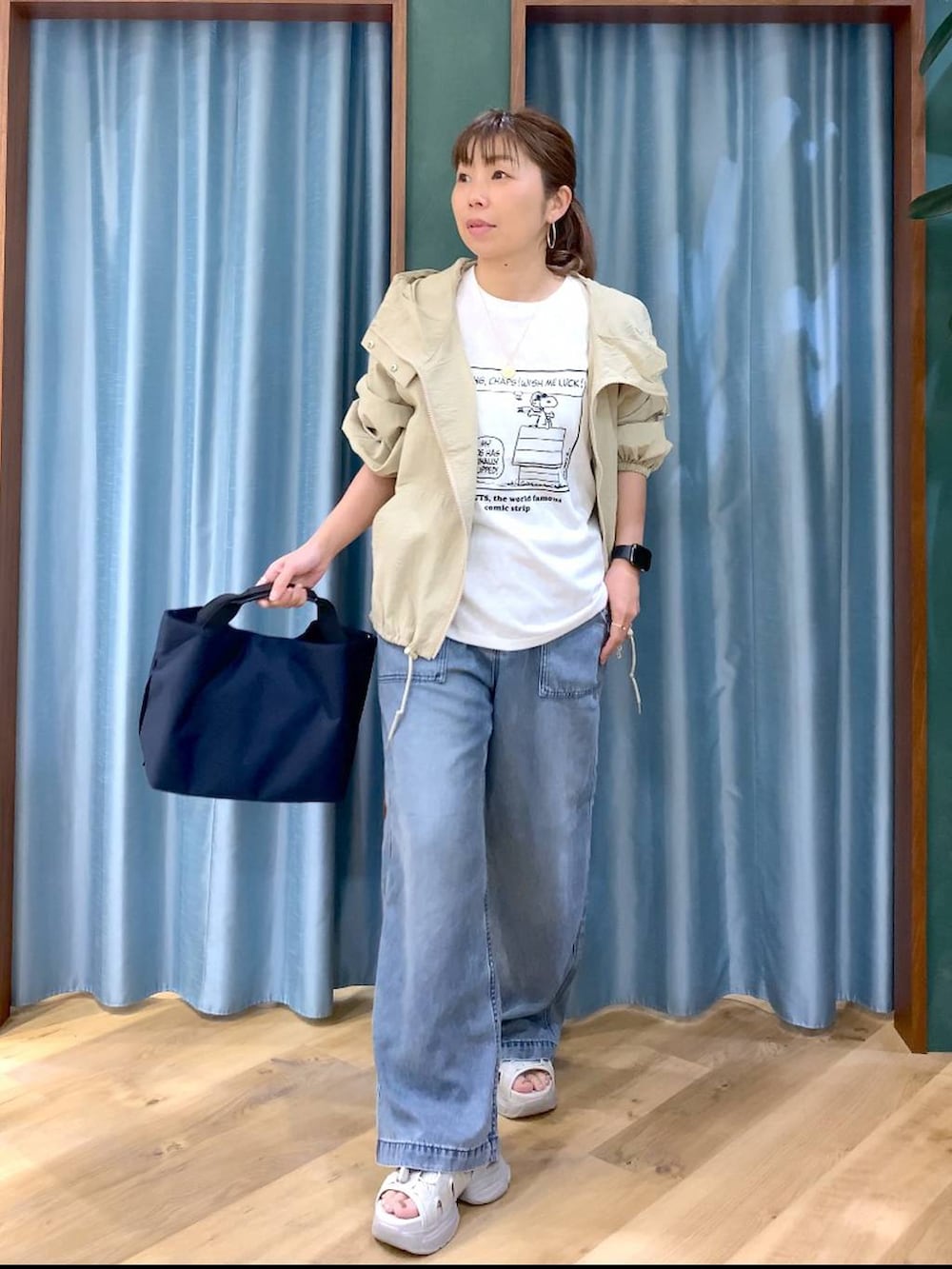 ブルー系のトートバッグ、ブルー系のデニムパンツ、ベージュ系のブルゾンを着用したレディースの春コーディネートの2枚目の写真