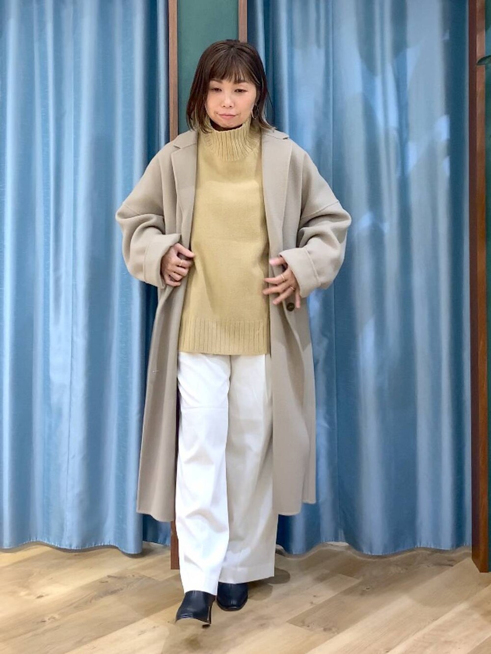 ベージュ系のニット/セーター、ベージュ系のチェスターコート、ブラック系のブーツを着用したレディースの秋コーディネートの5枚目の写真