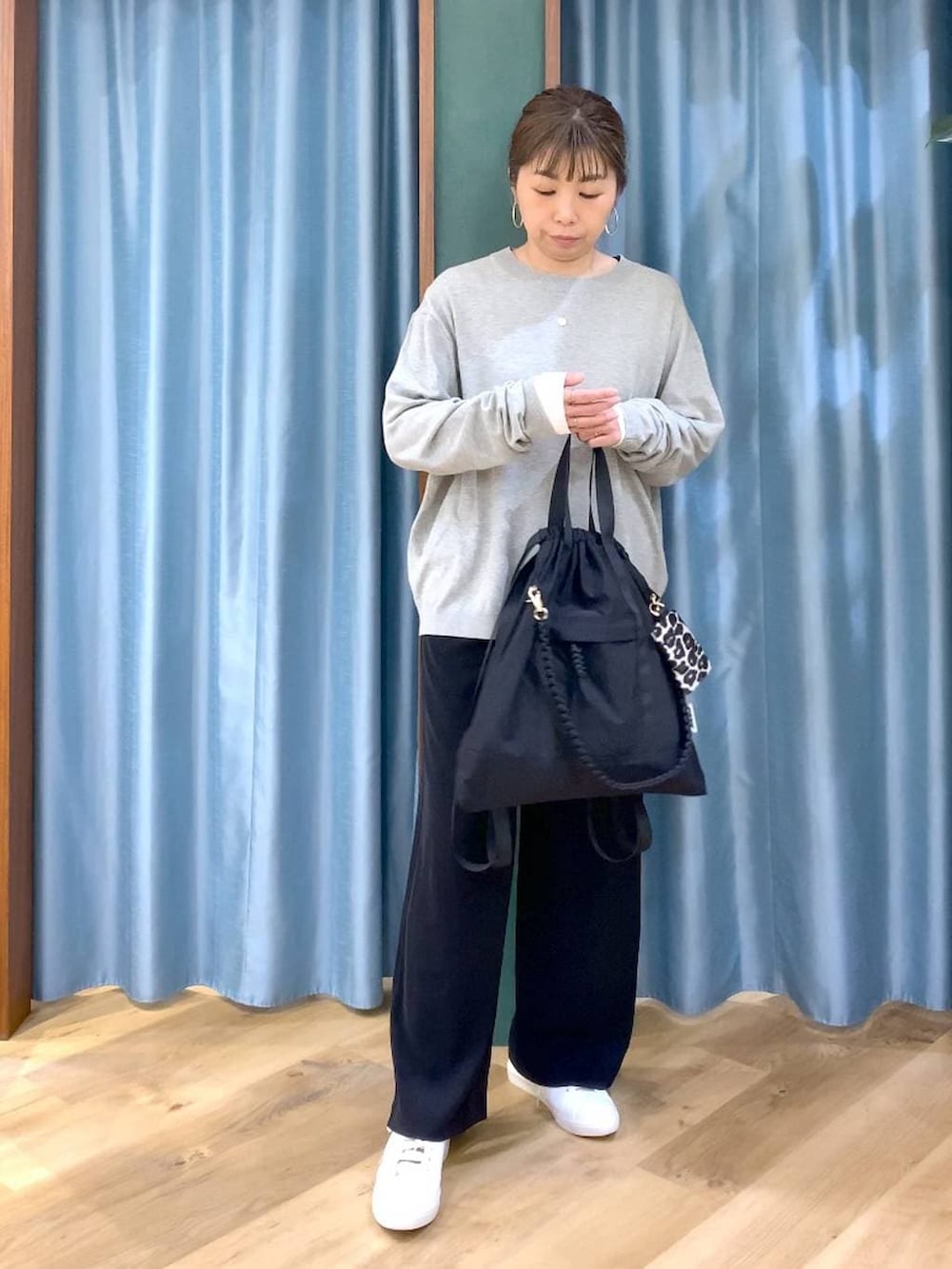 ブラック系のスラックス、ホワイト系のTシャツ/カットソー、グレー系のニット/セーターを着用したレディースの冬コーディネートの2枚目の写真