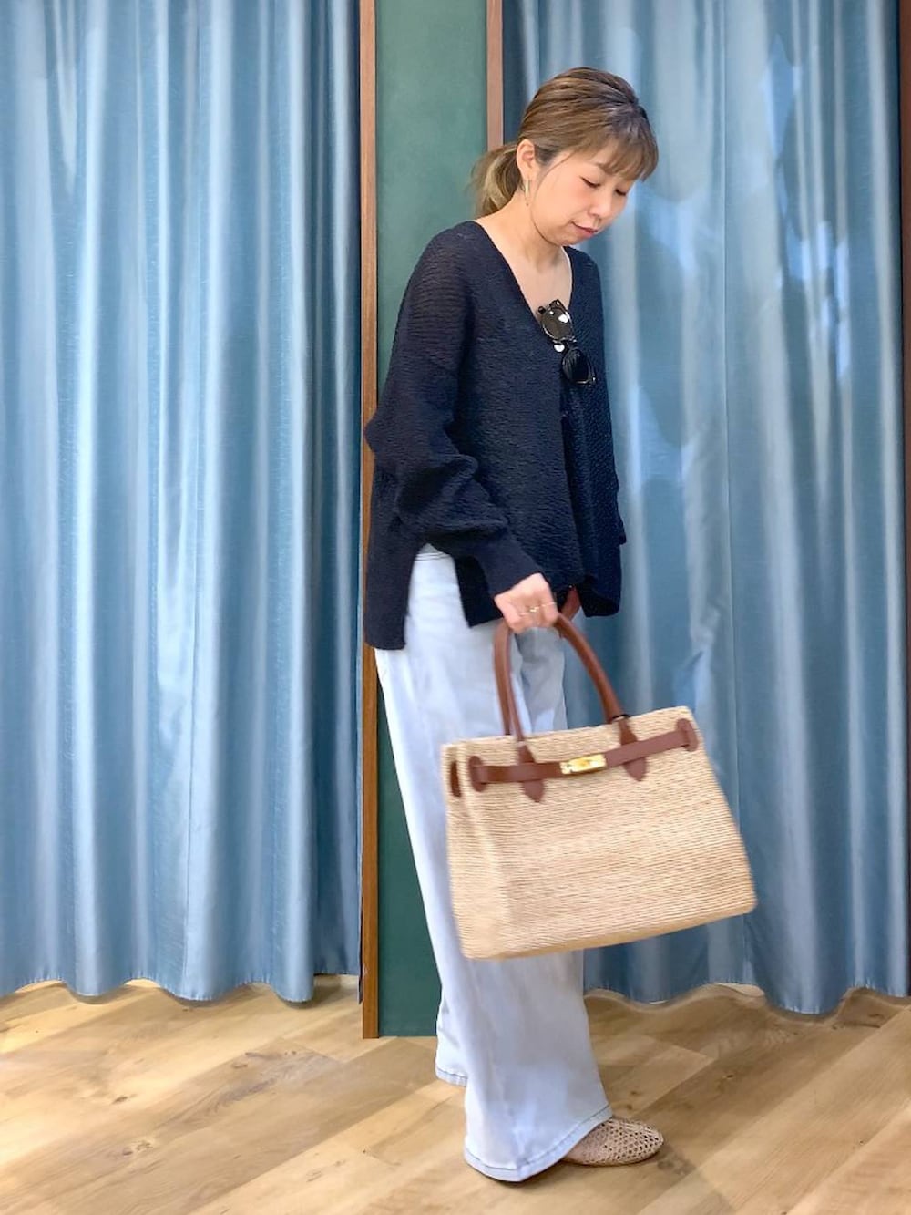 ホワイト系のタンクトップ、ブルー系のデニムパンツ、ブラック系のカーディガン/ボレロを着用したレディースの春コーディネートの3枚目の写真