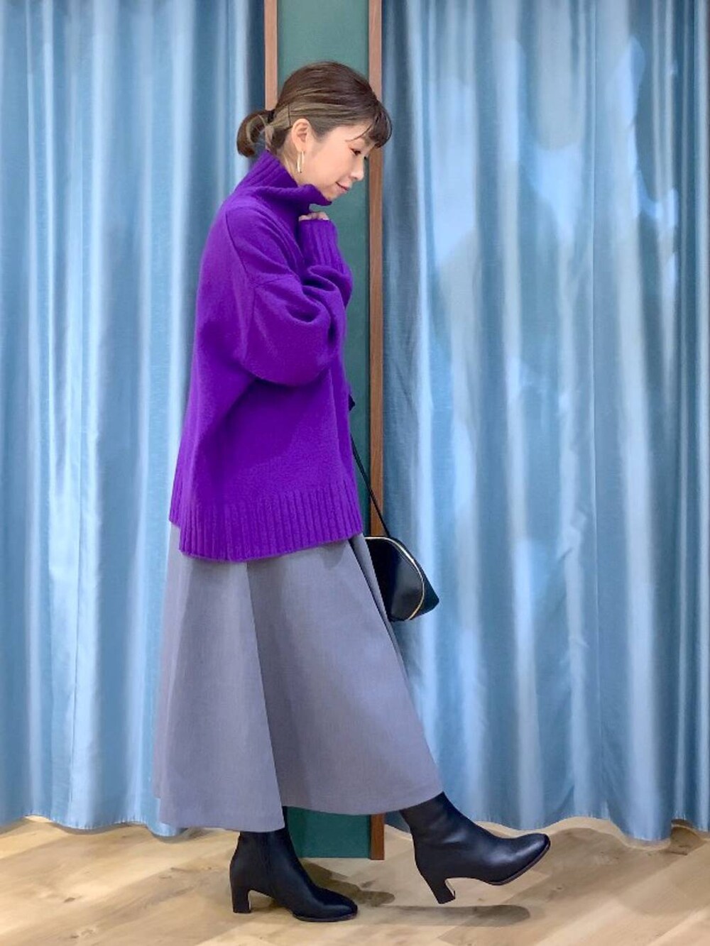 ブラック系のトートバッグ、グレー系のスカート、ブラック系のブーツを着用したレディースの秋コーディネートの2枚目の写真