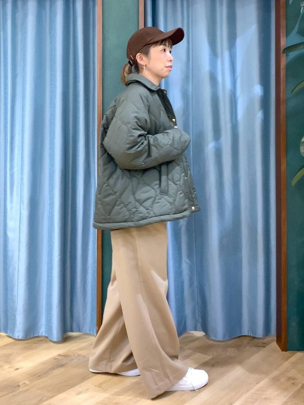 グリーン系のブルゾン、ブラウン系のニット/セーター、イエロー系のスラックスを着用したレディースの冬コーディネートの5枚目の写真