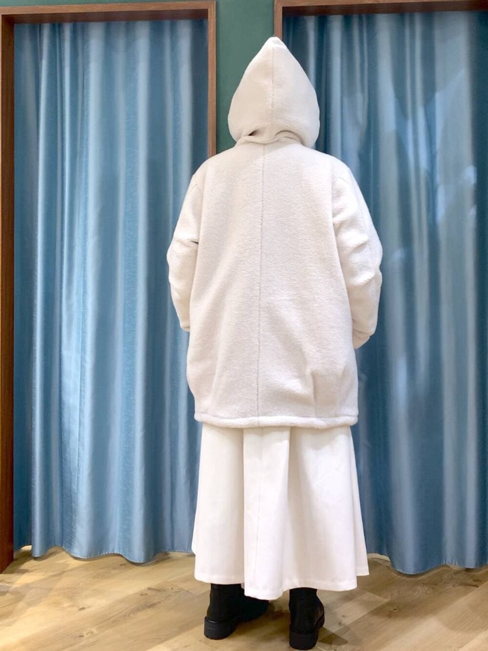 ブラック系のブーツ、ホワイト系のその他アウター、ホワイト系のスカートを着用したレディースの冬コーディネートの7枚目の写真