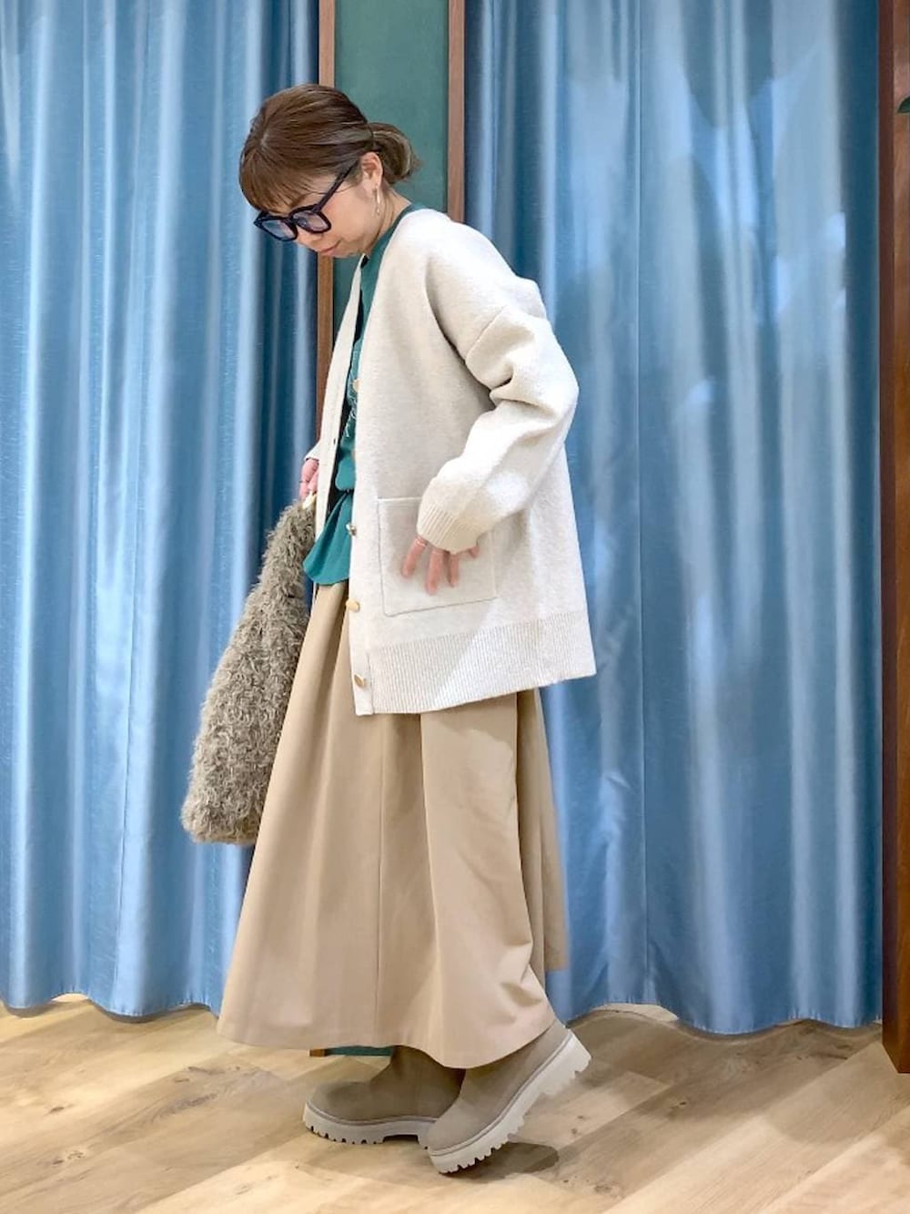 ベージュ系のハンドバッグ、ベージュ系のブーツ、グリーン系のTシャツ/カットソーを着用したレディースの冬コーディネートの5枚目の写真