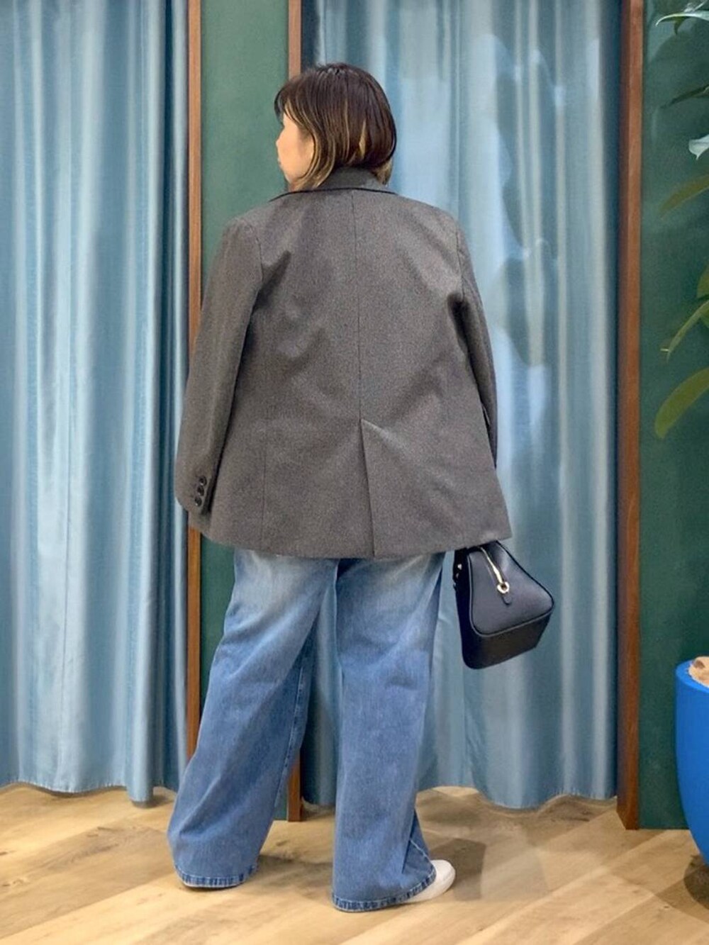 ブラック系のボストンバッグ、ホワイト系のスニーカー、ブルー系のデニムパンツを着用したレディースの秋コーディネートの5枚目の写真
