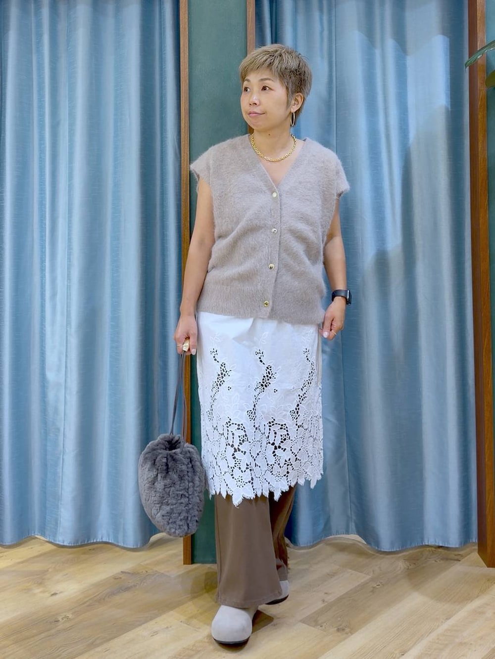 グレー系のハンドバッグ、ホワイト系のチュニック、ブラウン系のデニムパンツを着用したレディースの夏コーディネートの2枚目の写真