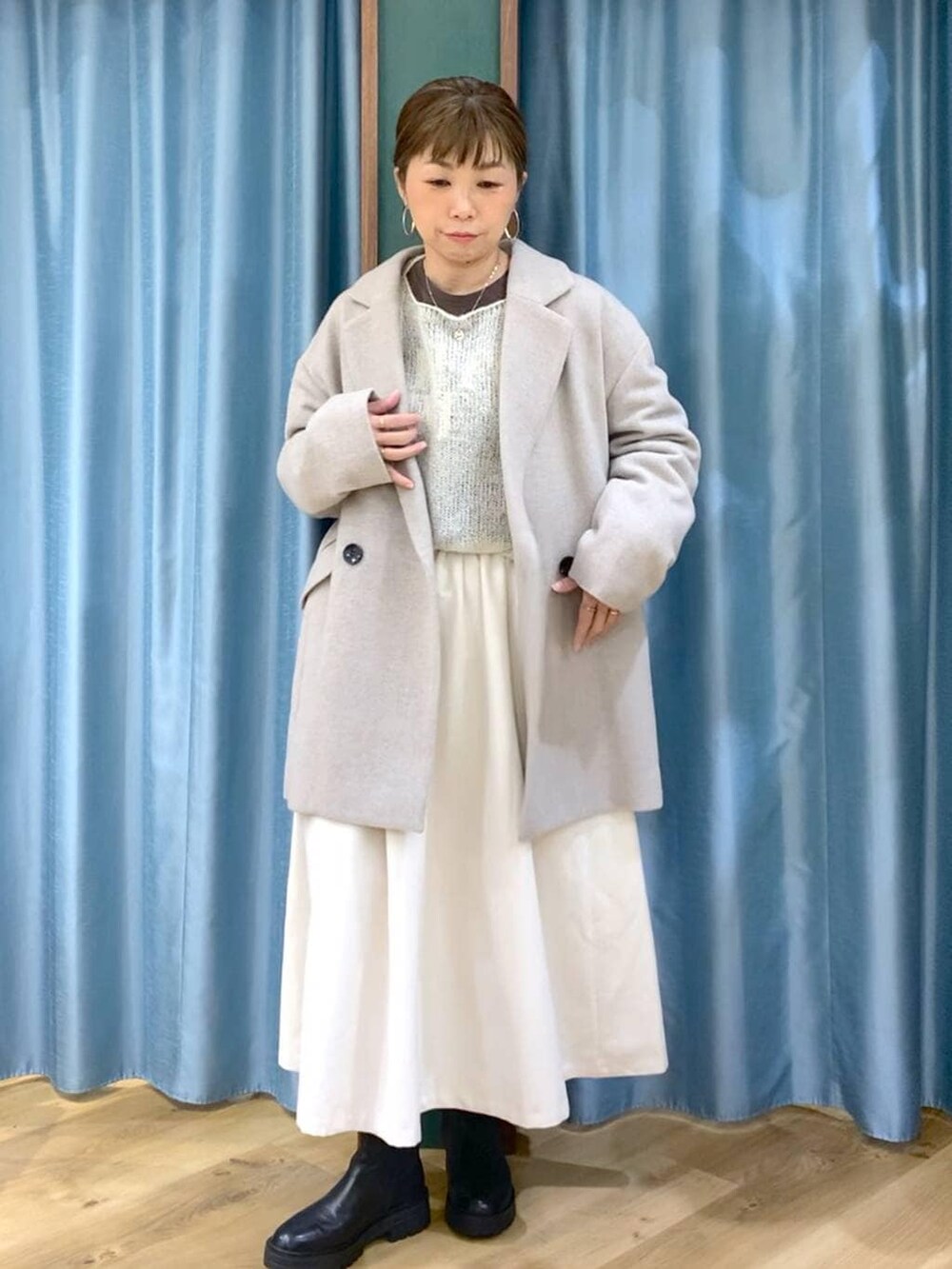 ブラック系のブーツ、ベージュ系のピーコート、ホワイト系のスカートを着用したレディースの冬コーディネートの7枚目の写真