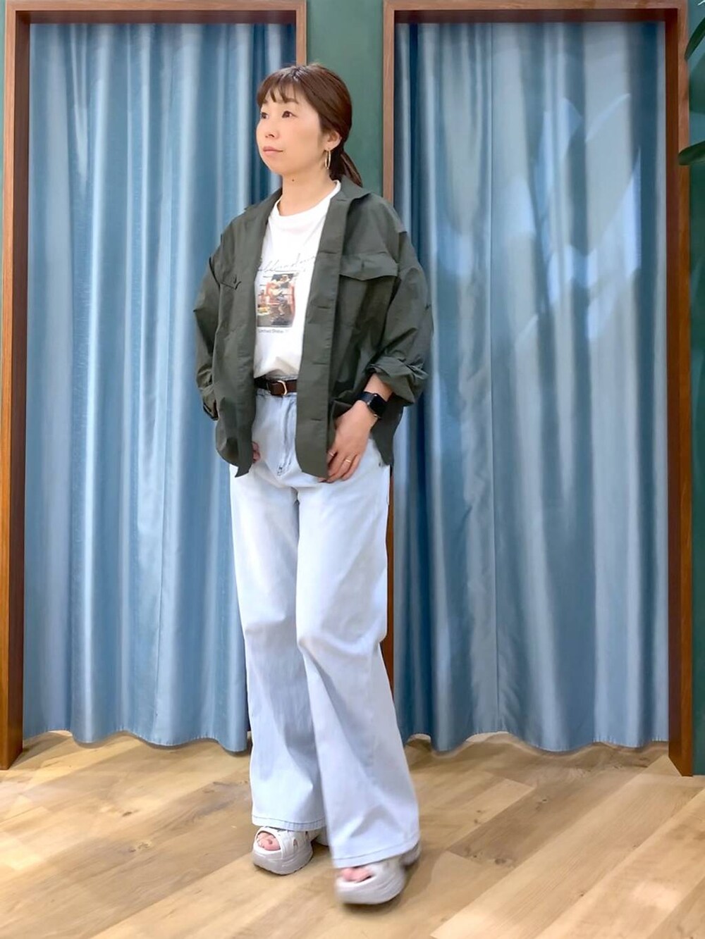 ブルー系のデニムパンツ、ホワイト系のTシャツ/カットソー、グレー系のサンダルを着用したレディースの春コーディネートの3枚目の写真