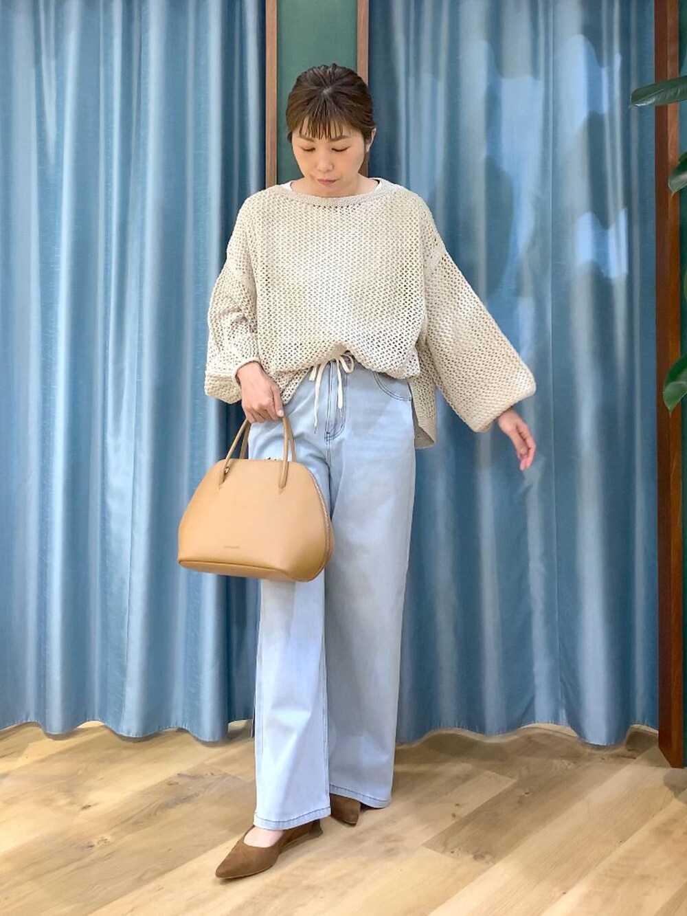 ベージュ系のニット/セーター、ブラウン系のトートバッグ、ホワイト系のTシャツ/カットソーを着用したレディースの冬コーディネートの3枚目の写真