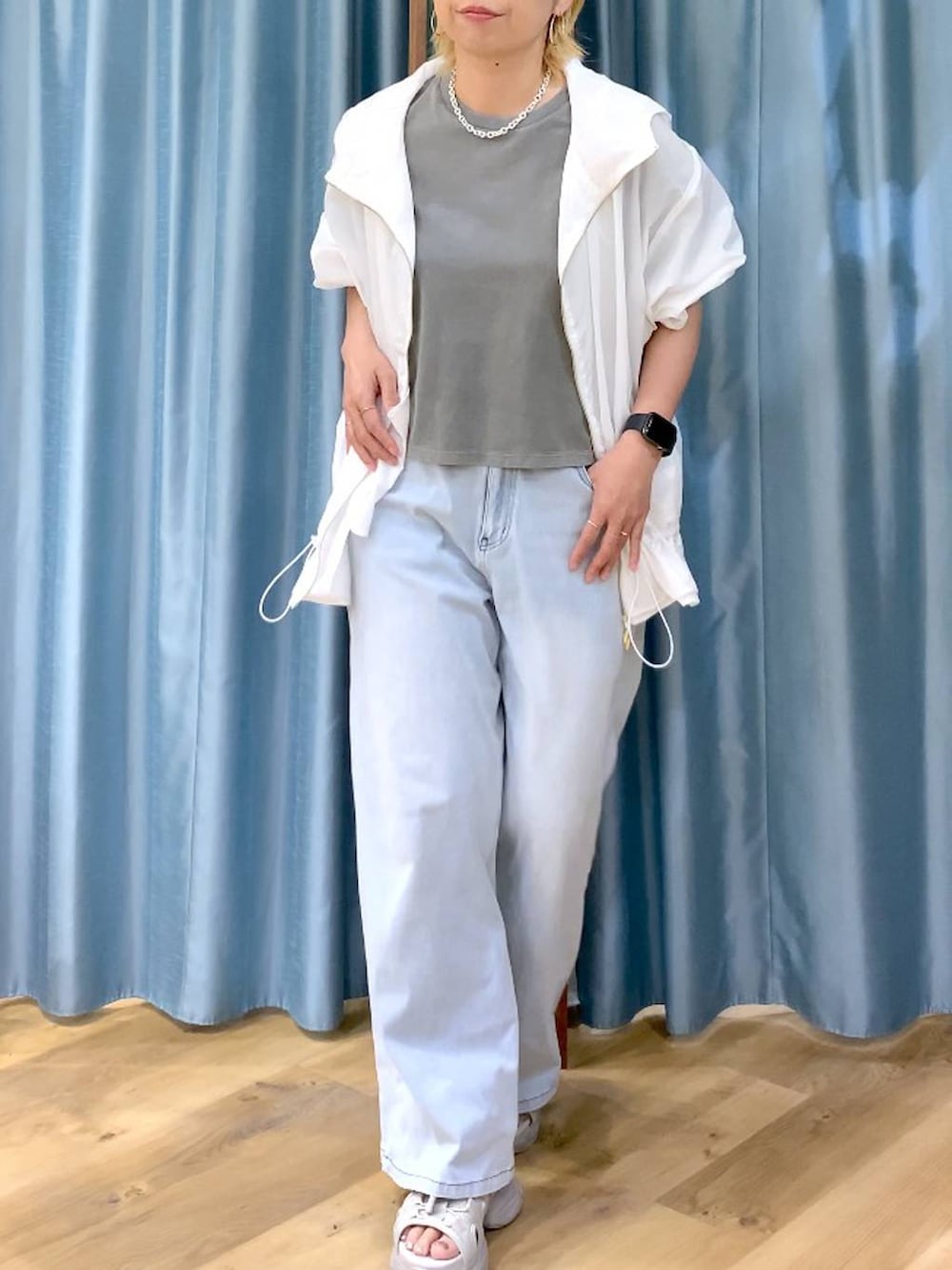 ブルー系のデニムパンツ、グレー系のサンダル、ホワイト系のブルゾンを着用したレディースの春コーディネートの7枚目の写真