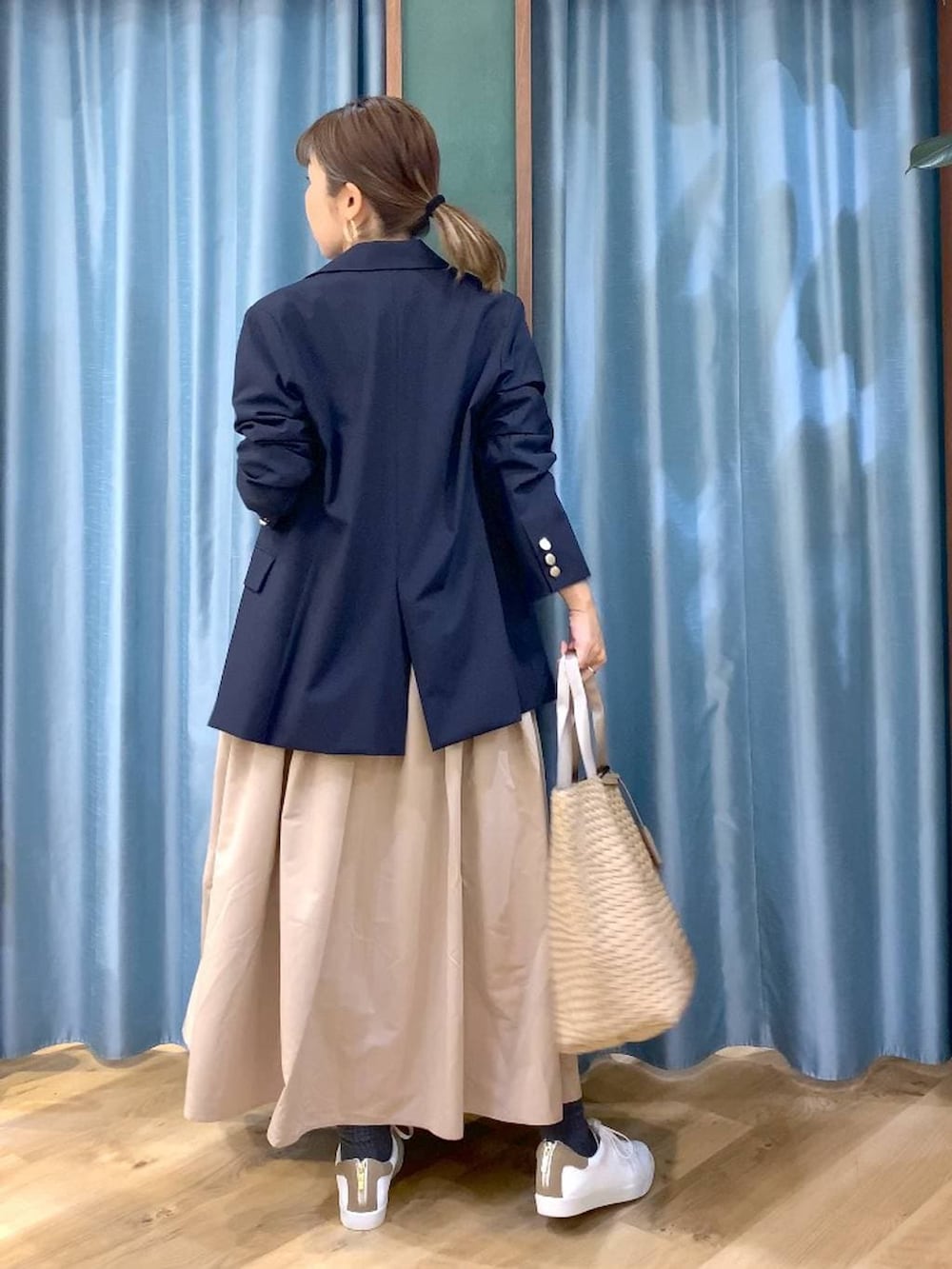 ベージュ系のスカート、ブルー系のテーラードジャケット、ベージュ系のトートバッグを着用したレディースの冬コーディネートの4枚目の写真