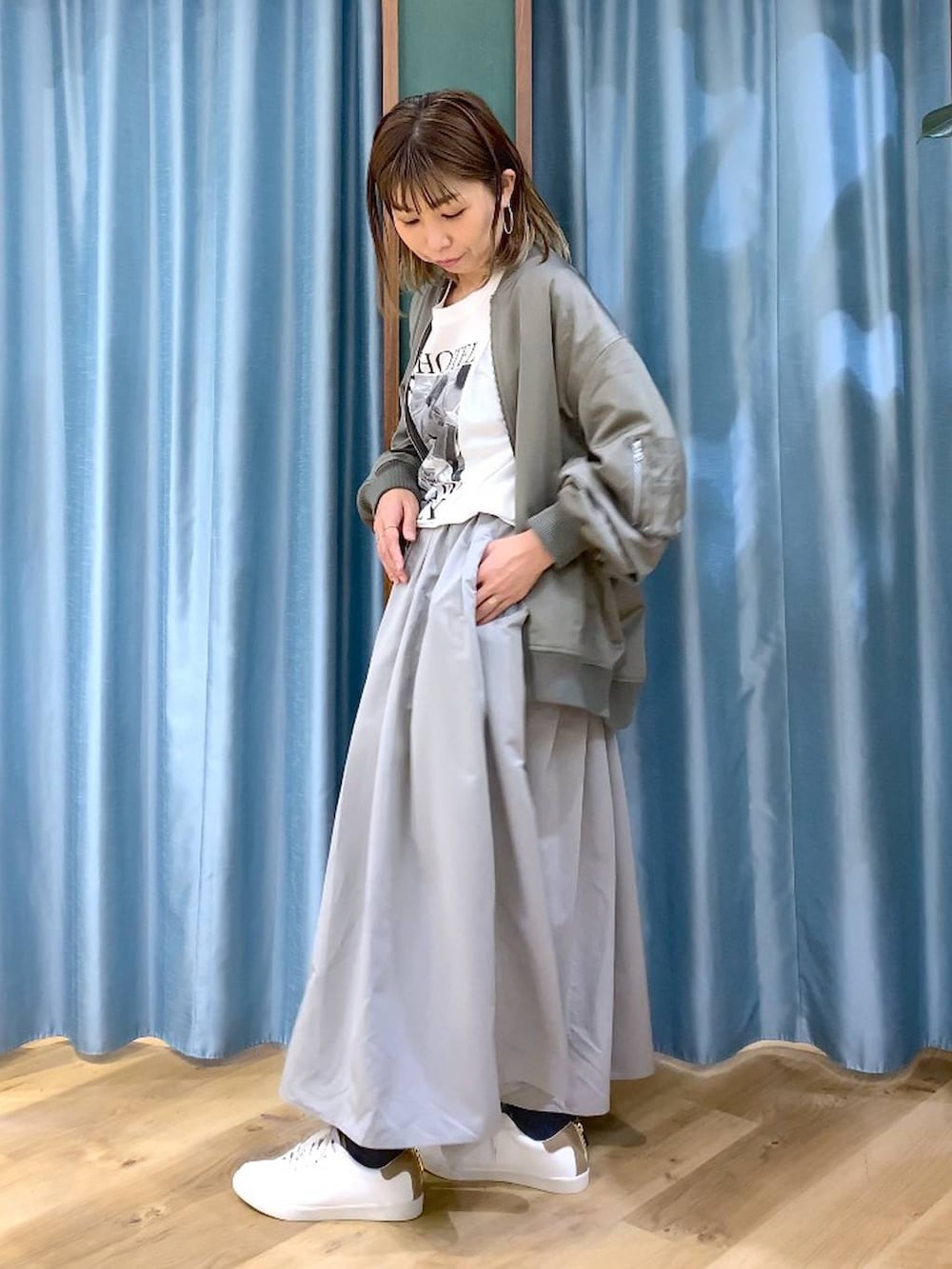 グレー系のスカート、グリーン系のMA-1、ホワイト系のTシャツ/カットソーを着用したレディースの冬コーディネートの2枚目の写真