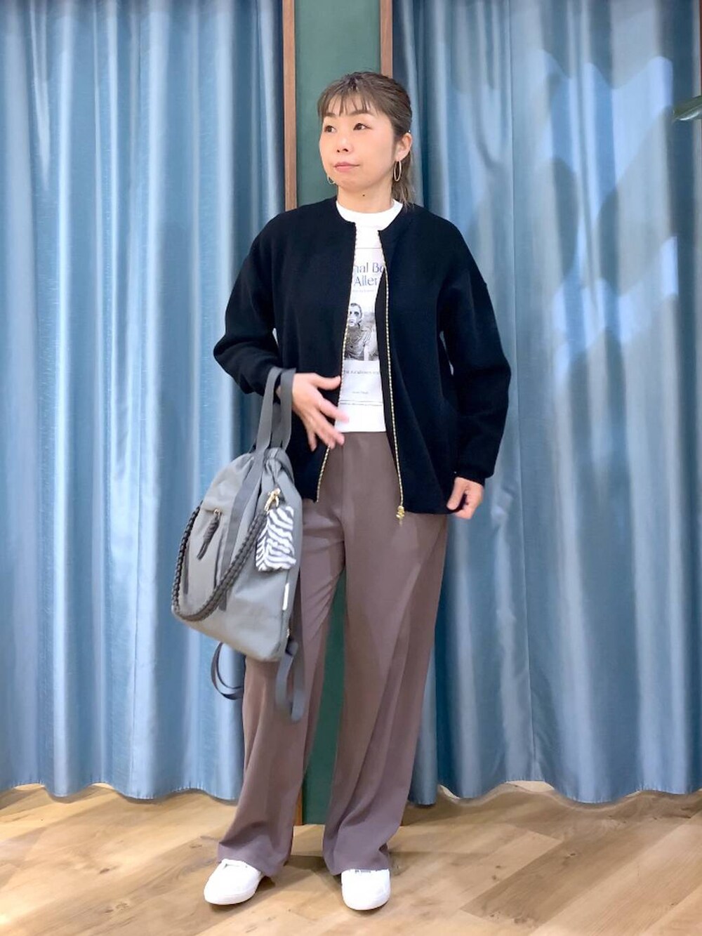 グリーン系のスラックス、ブラック系のカーディガン/ボレロ、グレー系のバックパック/リュックを着用したレディースの冬コーディネートの2枚目の写真