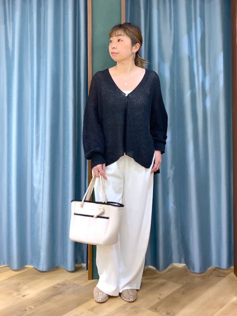 ホワイト系のスラックス、ブラック系のカーディガン/ボレロ、ホワイト系のトートバッグを着用したレディースの春コーディネートの3枚目の写真