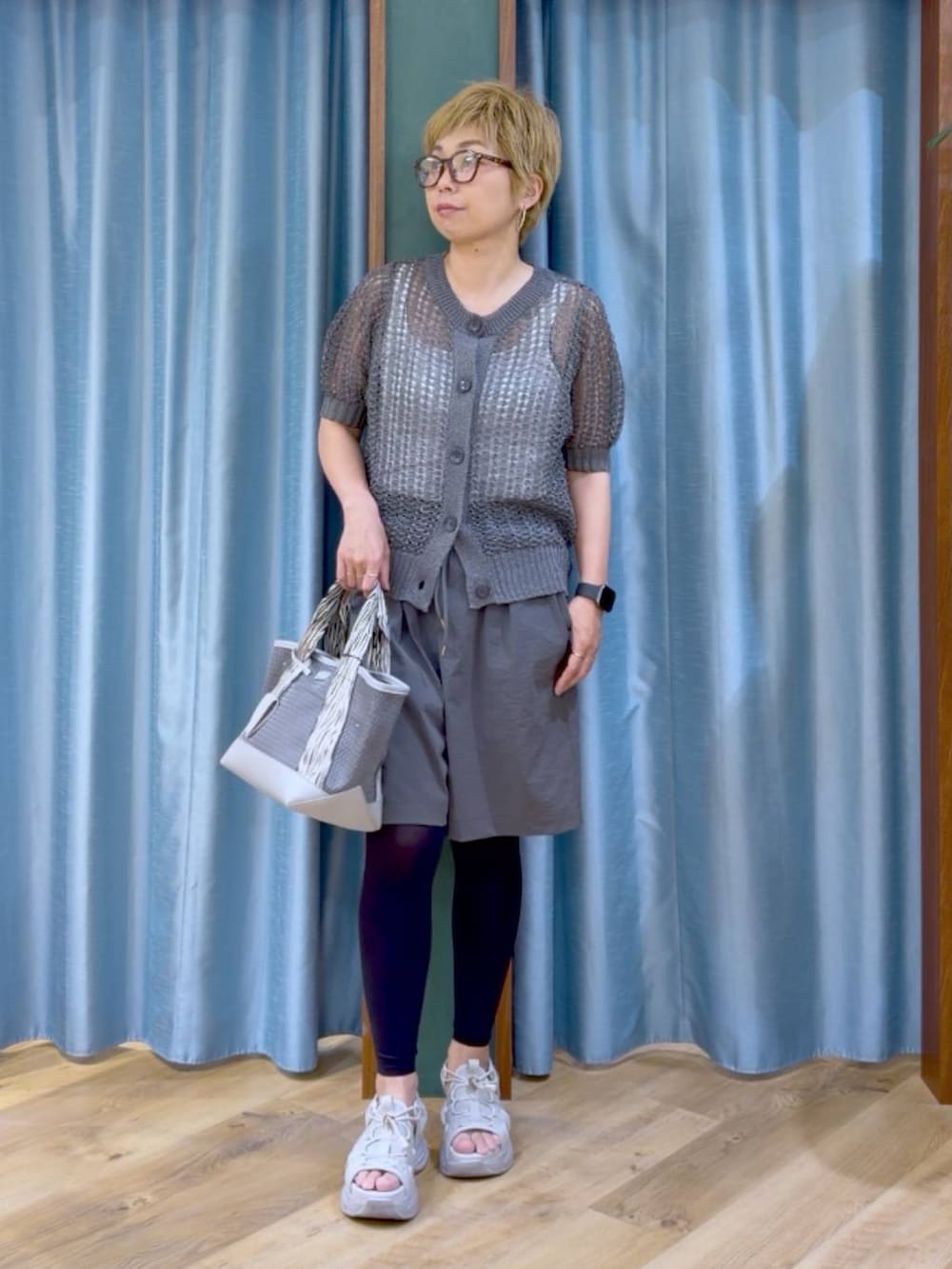 グレー系のトートバッグ、ホワイト系のタンクトップ、グレー系のサンダルを着用したレディースの夏コーディネートの2枚目の写真