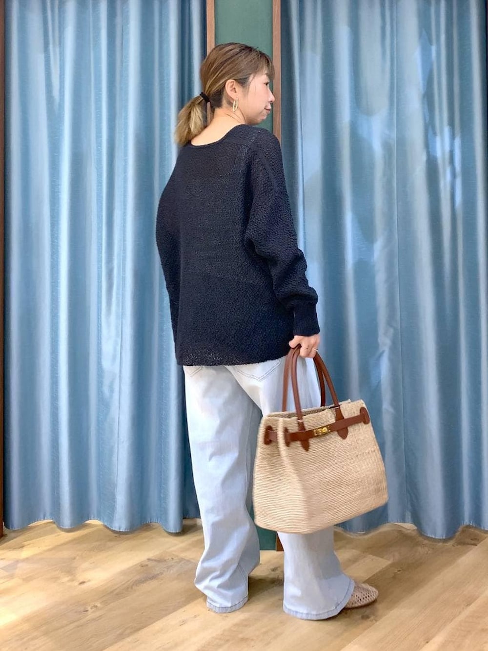 ホワイト系のタンクトップ、ブルー系のデニムパンツ、ブラック系のカーディガン/ボレロを着用したレディースの春コーディネートの4枚目の写真