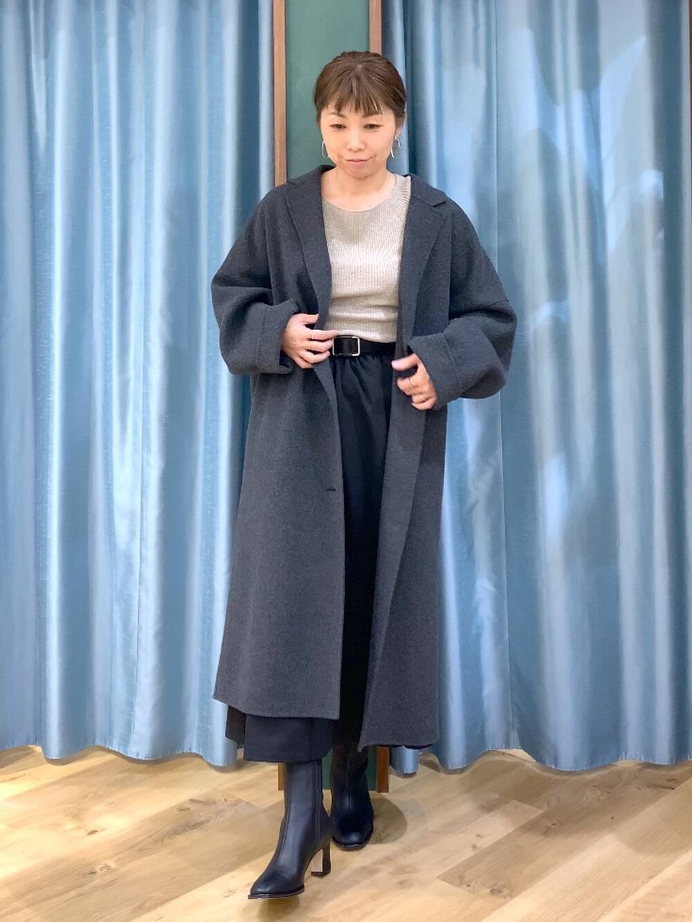 グレー系のチェスターコート、ブラック系のブーツ、ベージュ系のニット/セーターを着用したレディースの冬コーディネートの3枚目の写真