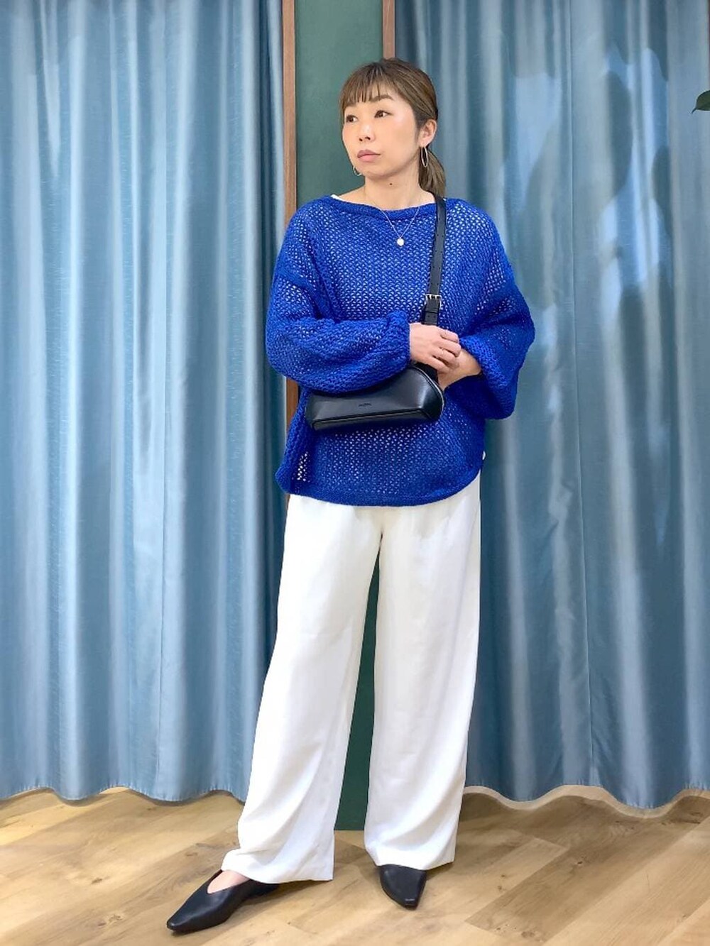 ホワイト系のスラックス、ブルー系のニット/セーター、ブラック系のパンプスを着用したレディースの冬コーディネートの2枚目の写真