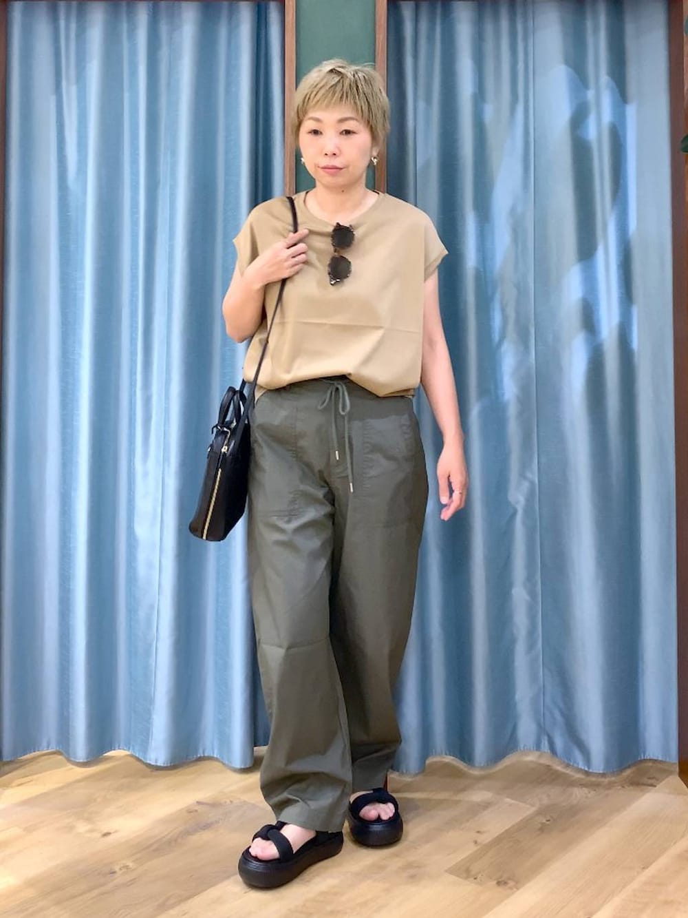 ブラック系のショルダーバッグ、グリーン系のカーゴパンツ、ブラック系のサンダルを着用したレディースの夏コーディネートの2枚目の写真