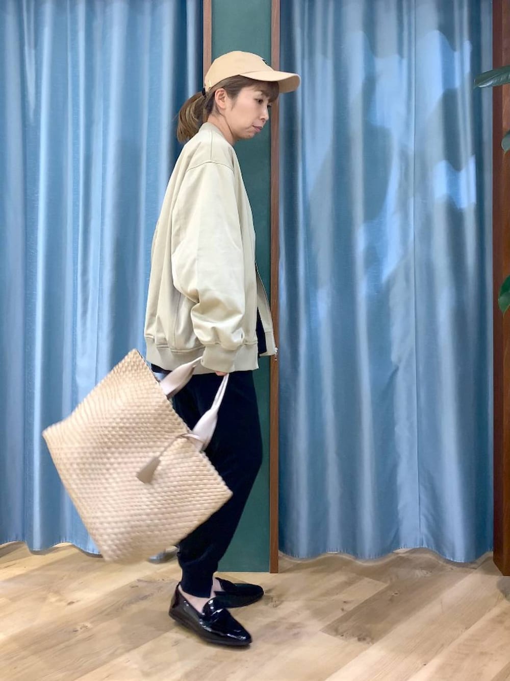 ベージュ系のMA-1、ブラック系のTシャツ/カットソー、ベージュ系のトートバッグを着用したレディースの冬コーディネートの3枚目の写真