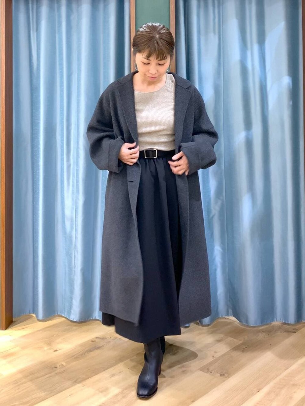 グレー系のチェスターコート、ブラック系のブーツ、ベージュ系のニット/セーターを着用したレディースの冬コーディネートの7枚目の写真