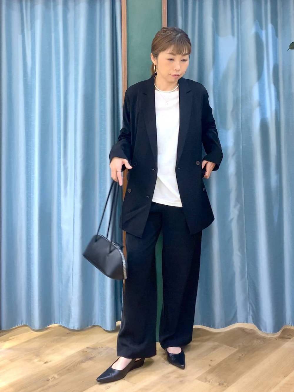 ブラック系のスラックス、ホワイト系のTシャツ/カットソー、ブラック系のテーラードジャケットを着用したレディースの冬コーディネートの2枚目の写真