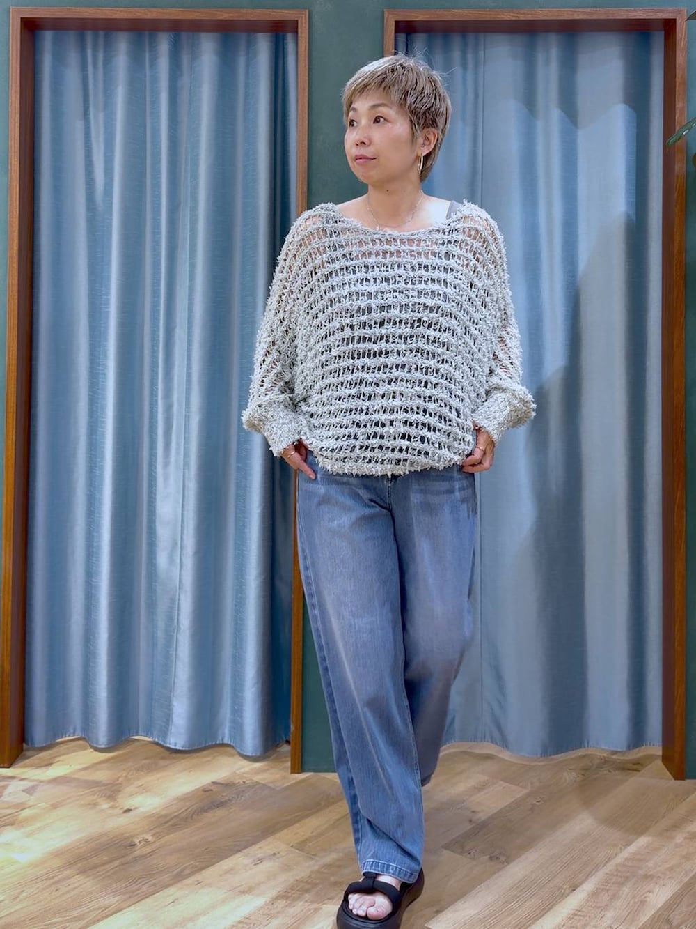 グレー系のタンクトップ、ブルー系のデニムパンツ、ブラック系のサンダルを着用したレディースの夏コーディネートの2枚目の写真