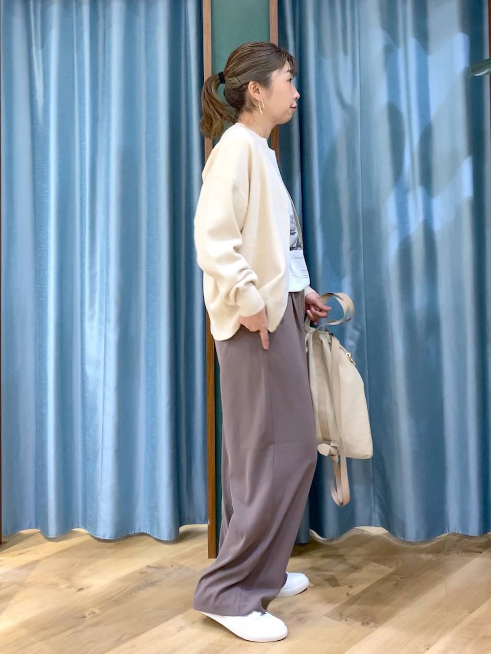 グリーン系のスラックス、ホワイト系のカーディガン/ボレロ、ベージュ系のバックパック/リュックを着用したレディースの冬コーディネートの4枚目の写真