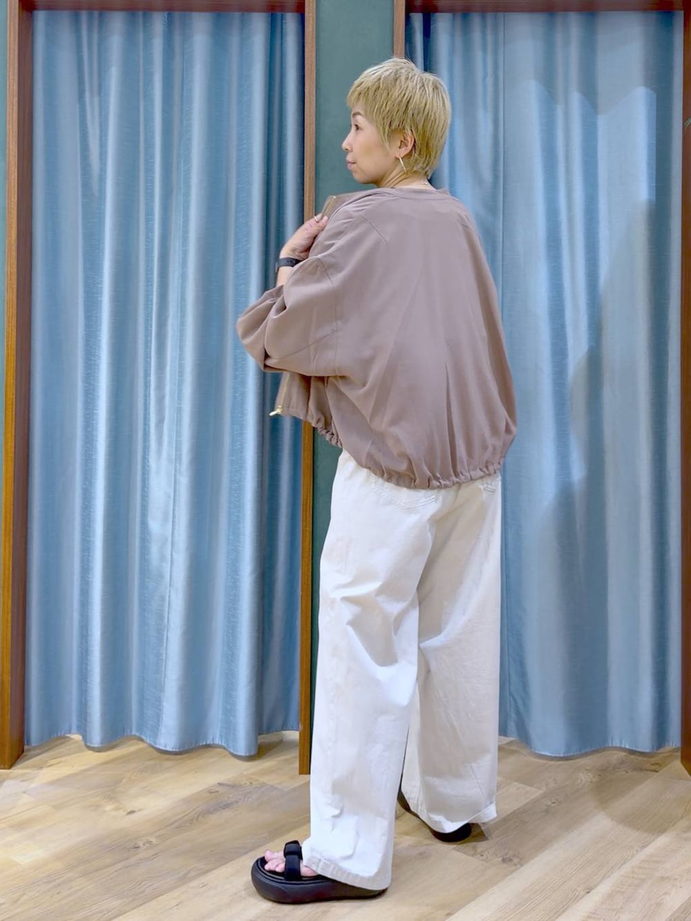 イエロー系のブルゾン、ベージュ系のその他パンツ、ブラック系のサンダルを着用したレディースの夏コーディネートの6枚目の写真