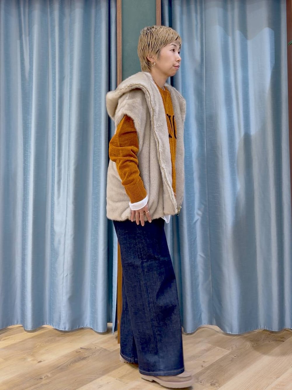 ブルー系のデニムパンツ、ベージュ系のローファー、イエロー系のニット/セーターを着用したレディースの秋コーディネートの5枚目の写真