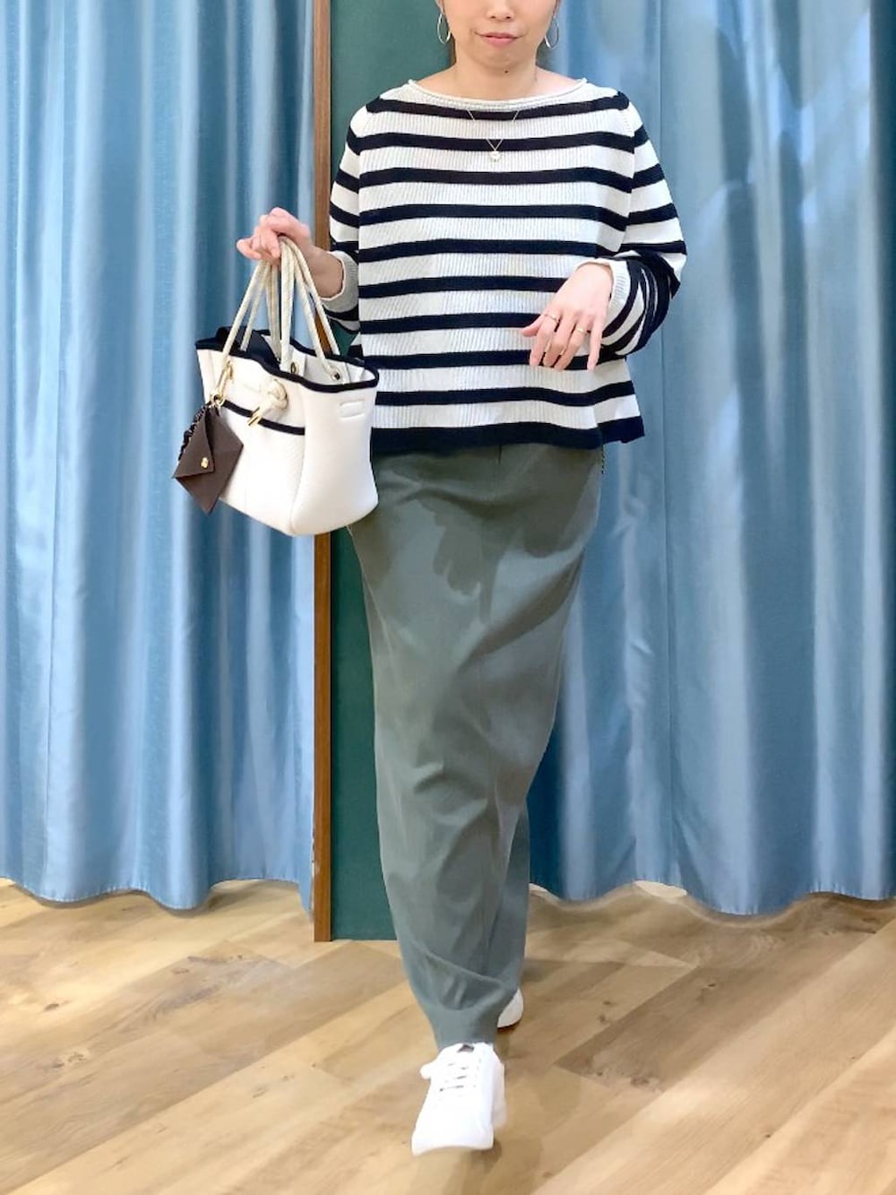 ベージュ系のニット/セーター、グリーン系のスカート、ホワイト系のトートバッグを着用したレディースの春コーディネートの8枚目の写真