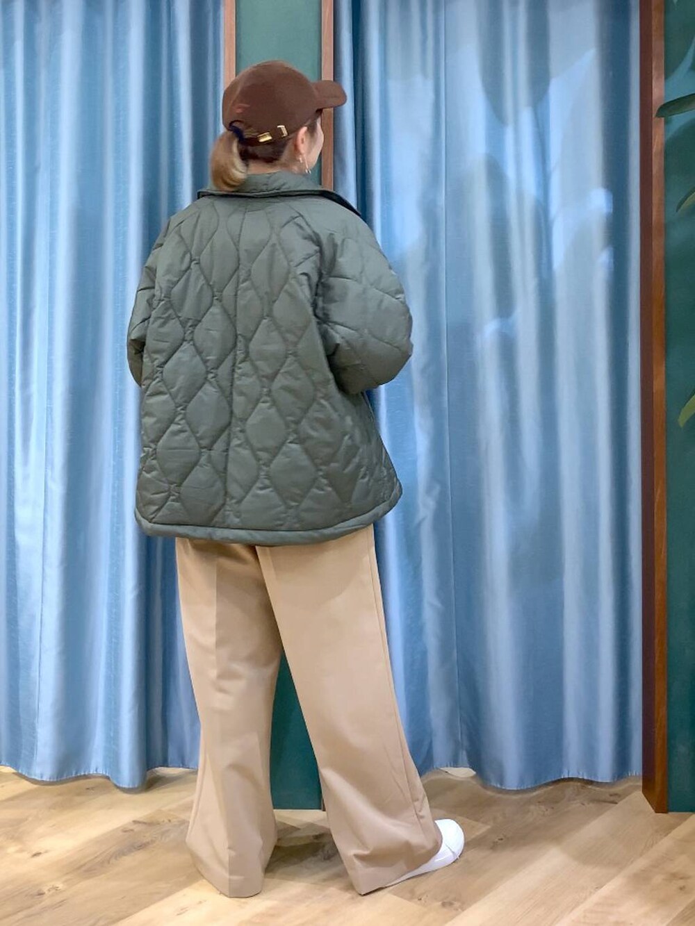 グリーン系のブルゾン、ブラウン系のニット/セーター、イエロー系のスラックスを着用したレディースの冬コーディネートの7枚目の写真