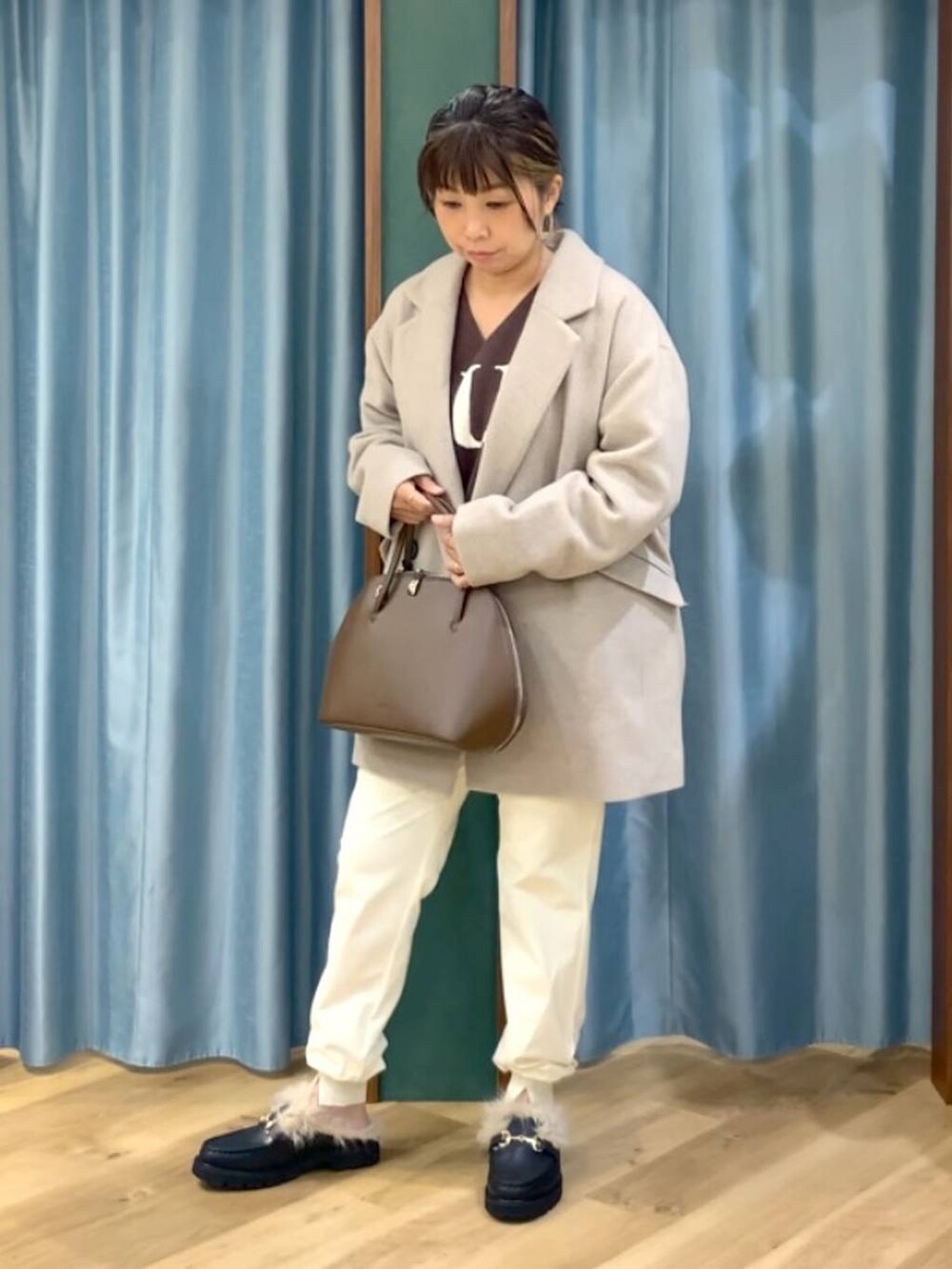 ブラウン系のトートバッグ、ブラウン系のニット/セーター、ベージュ系のピーコートを着用したレディースの秋コーディネートの2枚目の写真