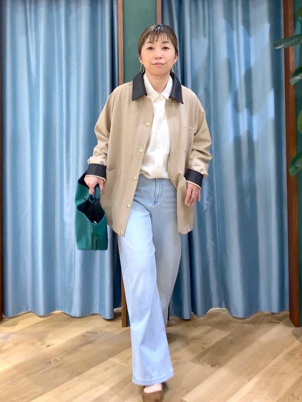 グリーン系のトートバッグ、ブルー系のデニムパンツ、ベージュ系のカバーオールを着用したレディースの冬コーディネートの4枚目の写真