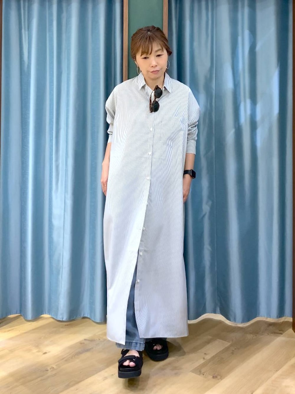 ブラック系のワンピース、ブルー系のデニムパンツ、ブラック系のサンダルを着用したレディースの春コーディネートの2枚目の写真