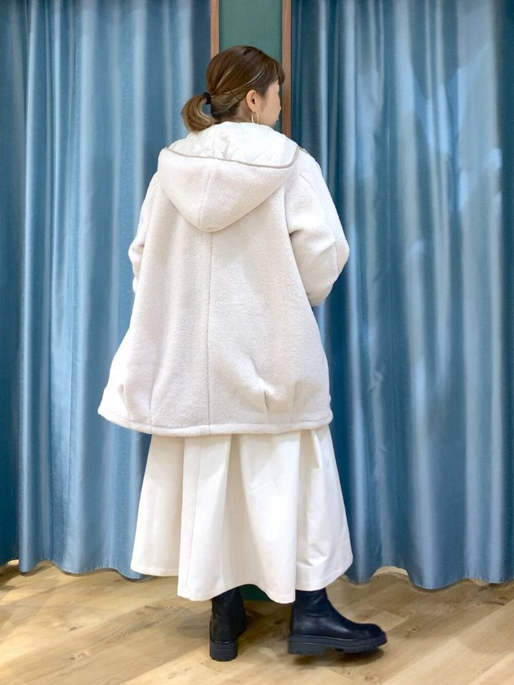 ブラック系のブーツ、ホワイト系のその他アウター、ホワイト系のスカートを着用したレディースの冬コーディネートの4枚目の写真